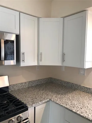 a kitchen with granite countertop white cabinets and a stove
