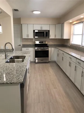 a kitchen with stainless steel appliances granite countertop a sink dishwasher and cabinets