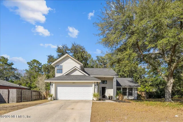 a front view of a house with a garden and tree