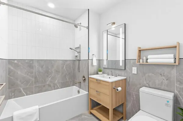 a bathroom with a sink a toilet a mirror and bathtub