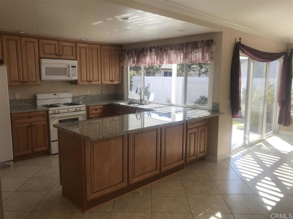 11417 Poblado Road San Diego, CA 92127 - Photo 24 of 37 a kitchen with kitchen island granite countertop a sink stove and cabinets