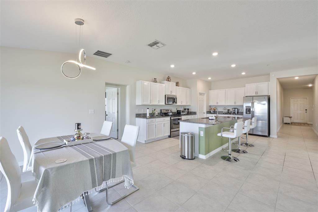 13575 Willow Bluestar Loop Riverview, FL 33579 - Photo 14 of 48 a kitchen with a dining table chairs wooden floor appliances and cabinets
