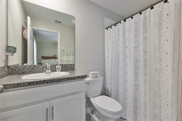 a bathroom with a granite countertop toilet sink and mirror