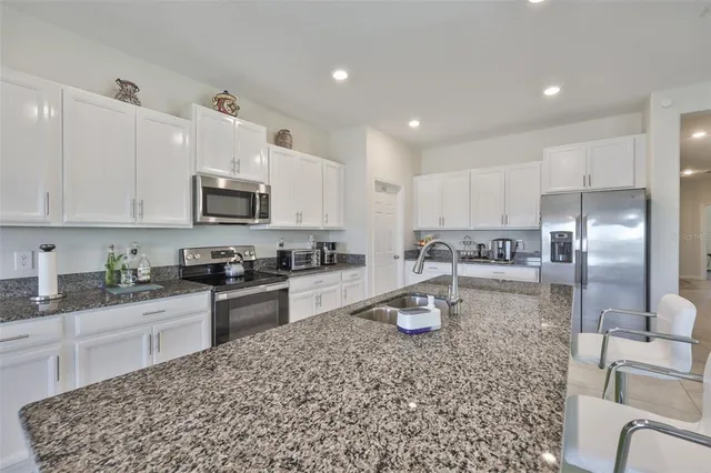 a kitchen with stainless steel appliances granite countertop a sink refrigerator and cabinets