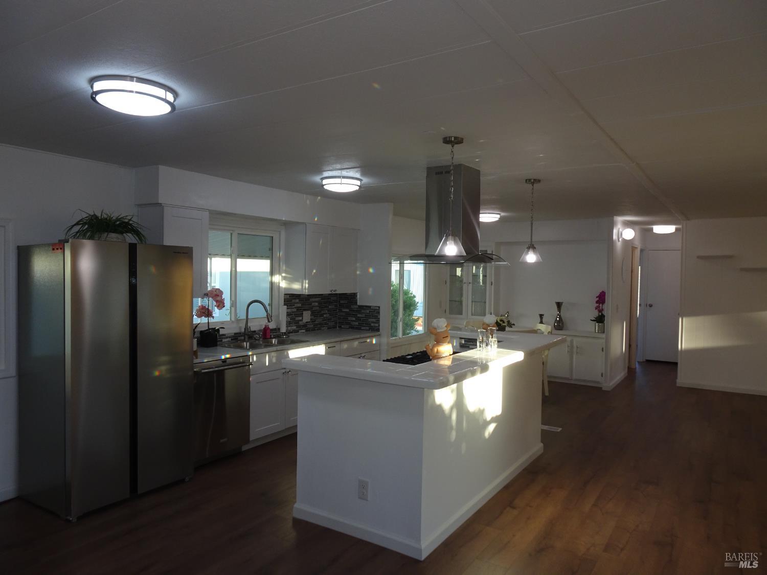 a kitchen with stainless steel appliances granite countertop a sink a stove a refrigerator a washer dryer and dining table