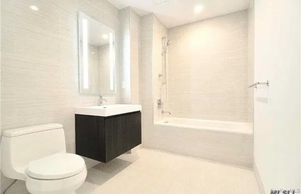 a bathroom with a bathtub shower sink vanity and toilet