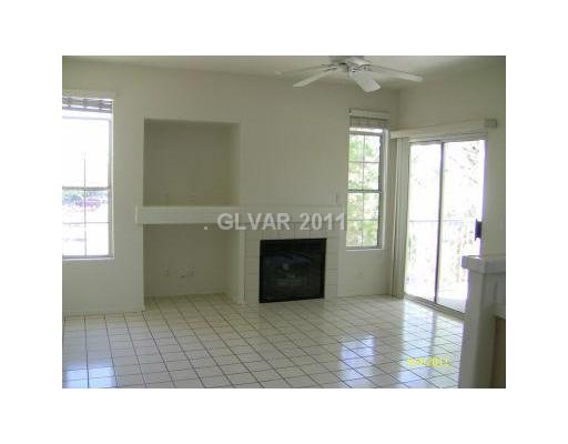 2201 Ramsgate Drive, Unit 128 Henderson, NV 89074 - Photo 2 of 20 Living Room. LIVING ROOM WITH COZY FIREPLACE, MEDIA NICHE, CEILING FAN, TILE FLOOR AND SLIDING GLASS DOOR TO THE BALCONY