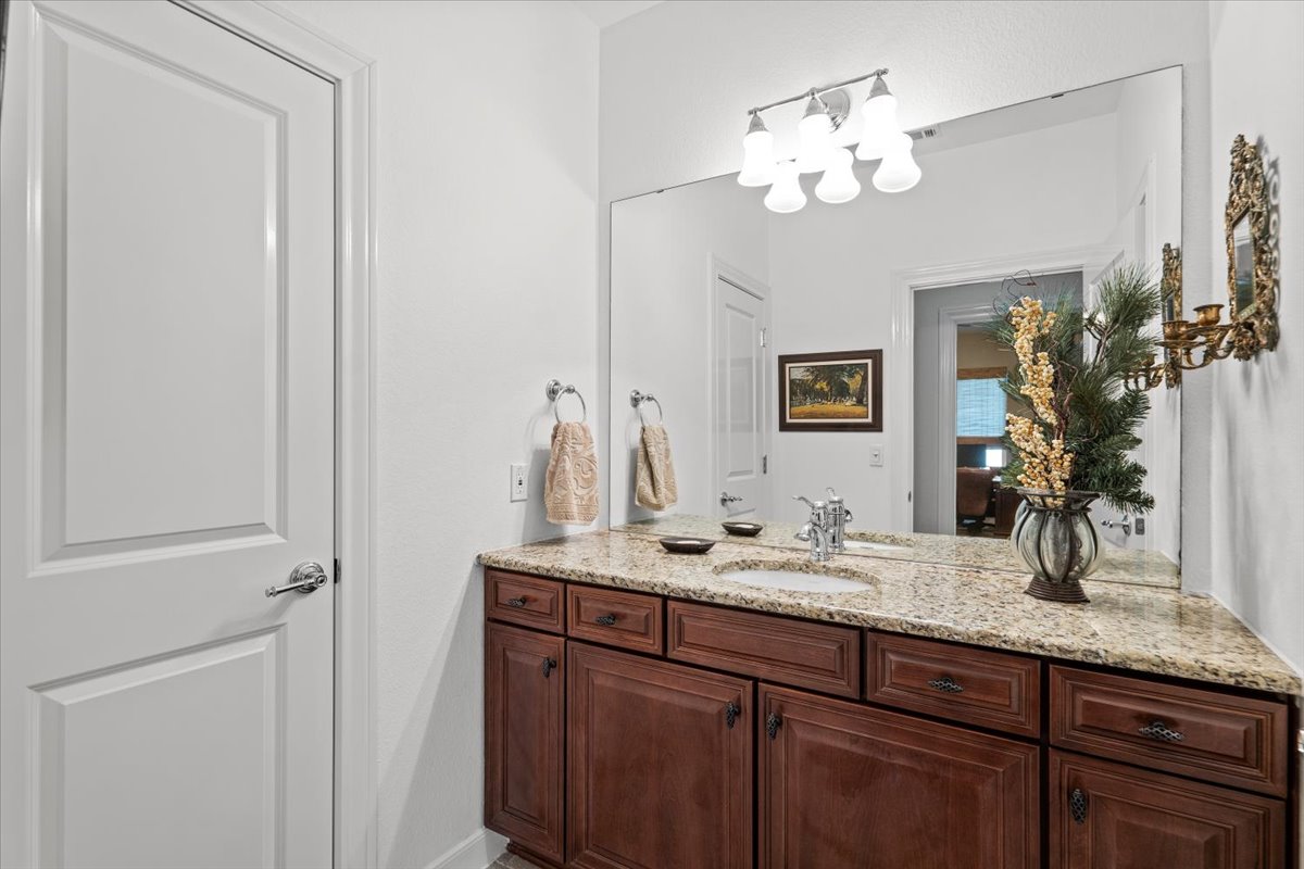 503 Breezeway Lane Georgetown, TX 78633 - Photo 29 of 38 A refined bathroom featuring a rich wood vanity with granite counters and a large, well-lit mirror.