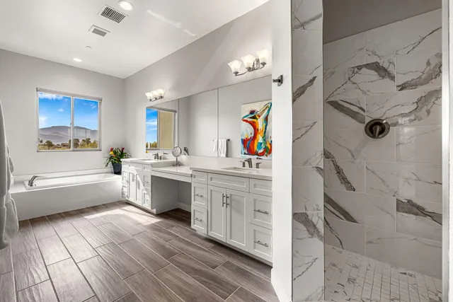 a large white kitchen with a lot of counter space and wooden floor