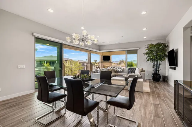 a living room with furniture a chandelier and a dining table with wooden floor
