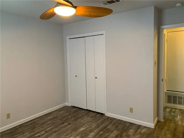 an empty room with a chandelier fan and wooden floor
