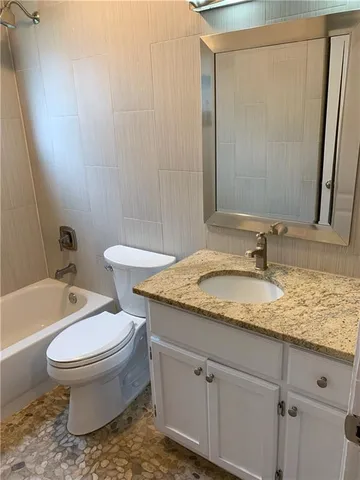 a bathroom with a granite countertop sink toilet and shower