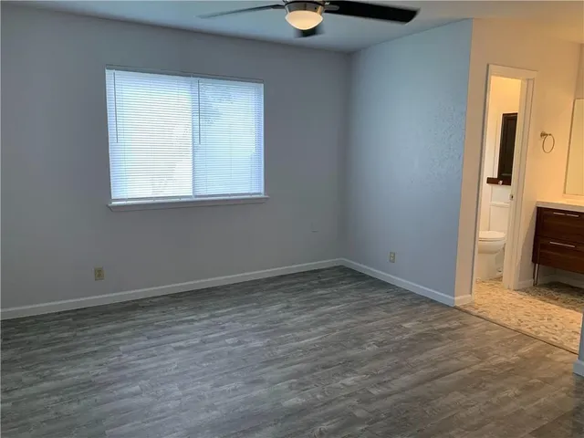 an empty room with wooden floor mirror and windows