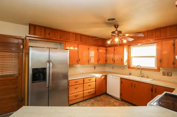 a kitchen with stainless steel appliances kitchen island granite countertop a sink refrigerator and cabinets