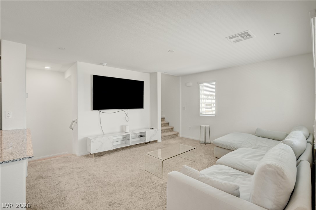 6924 Spicy Merlot Street North Las Vegas, NV 89086 - Photo 7 of 83 A cozy, well-lit living room offers plush carpeting and a modern entertainment setup, ideal for relaxation.