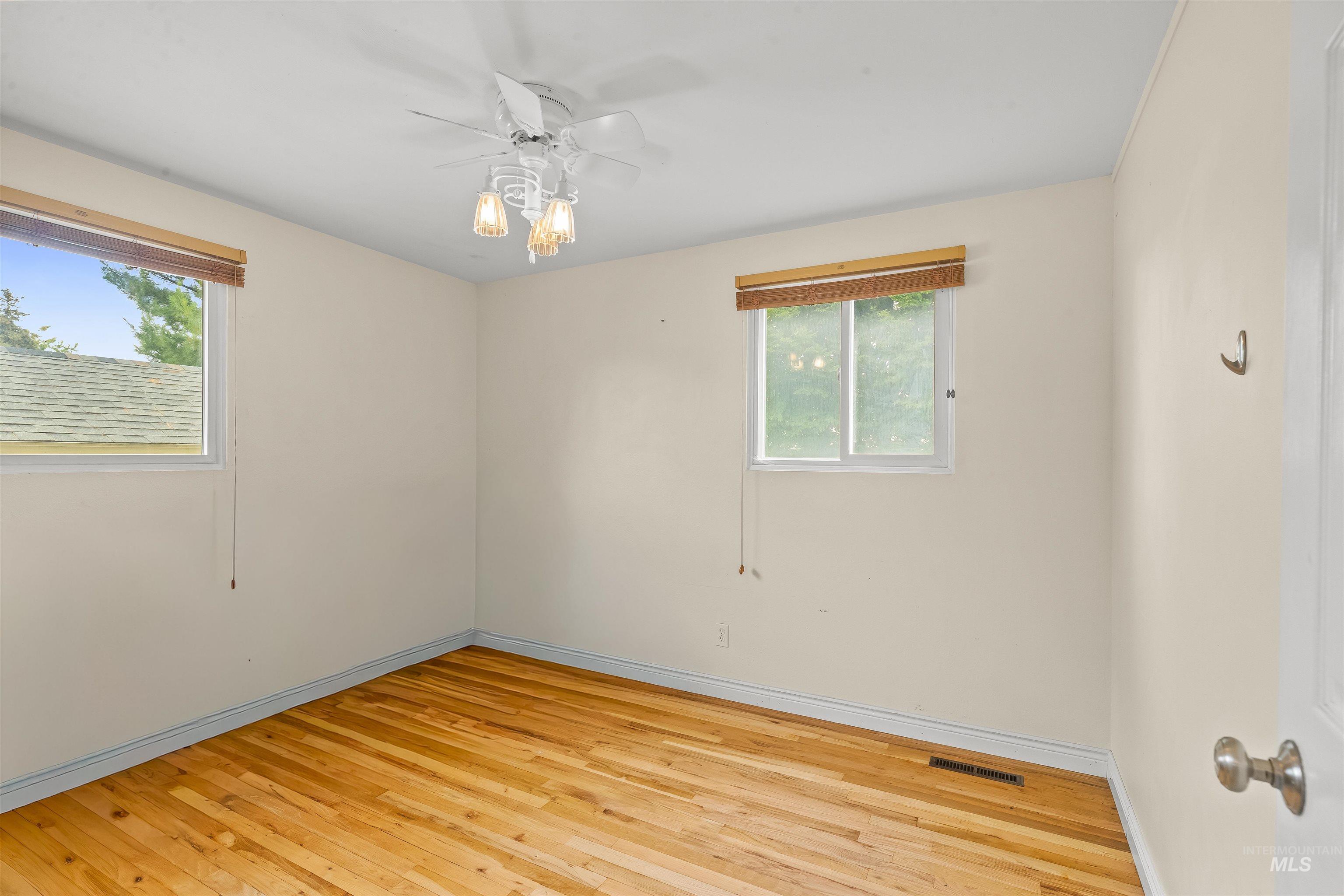 3620 18th Street Lewiston, ID 83501 - Photo 13 of 32 Interior space featuring wood-finish flooring, two windows with wood blinds, and a ceiling fan with integrated lighting