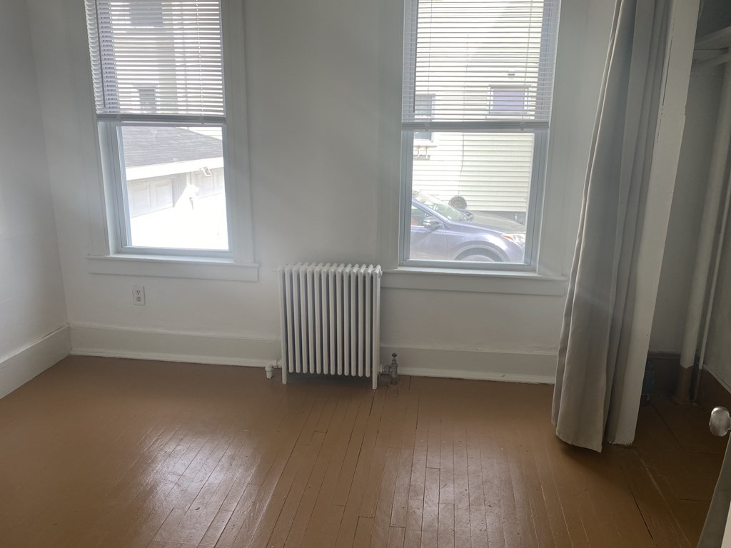 19 Meacham Street, Unit 1 Somerville, MA 02145 - Photo 7 of 11 an empty room with wooden floor and windows