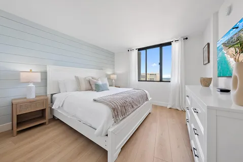a bedroom with a bed lamp on desk and a window