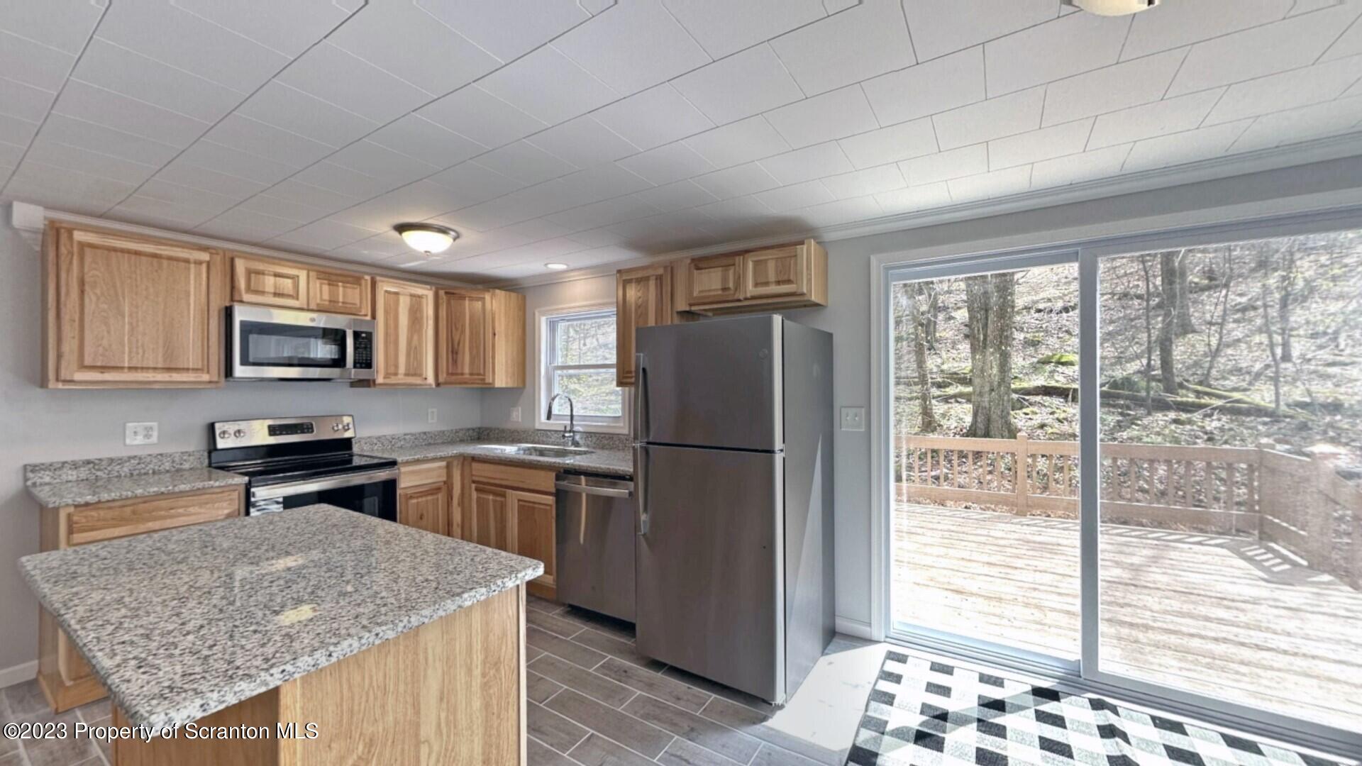 1013 Hemlock Way Newfoundland, PA 18445 - Photo 20 of 44 a kitchen with a refrigerator a stove a sink and a wooden cabinets