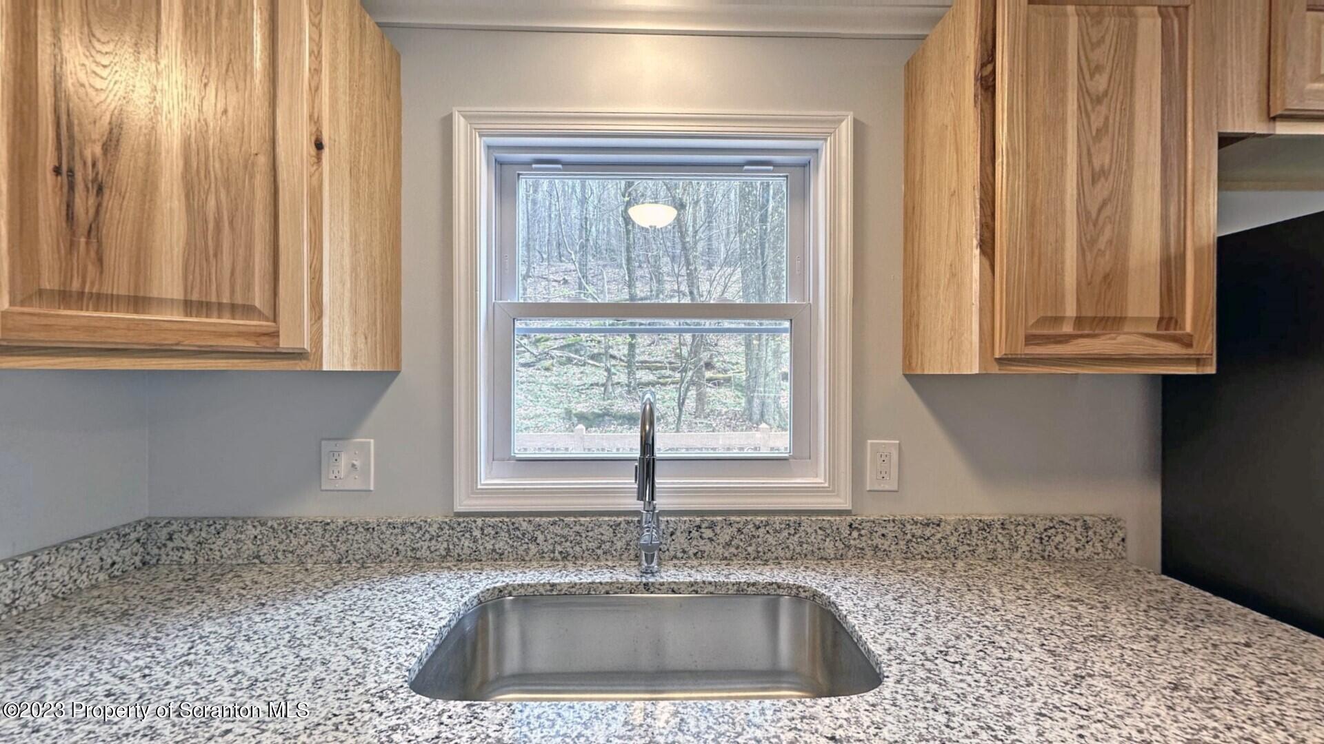 1013 Hemlock Way Newfoundland, PA 18445 - Photo 23 of 44 a kitchen with granite countertop a sink window and cabinets