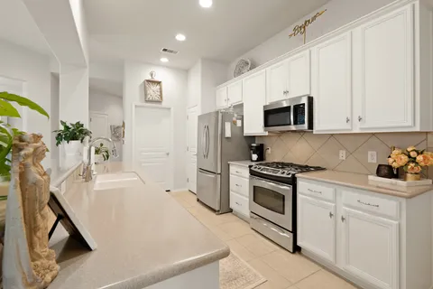 a kitchen with stainless steel appliances white cabinets and a stove top oven