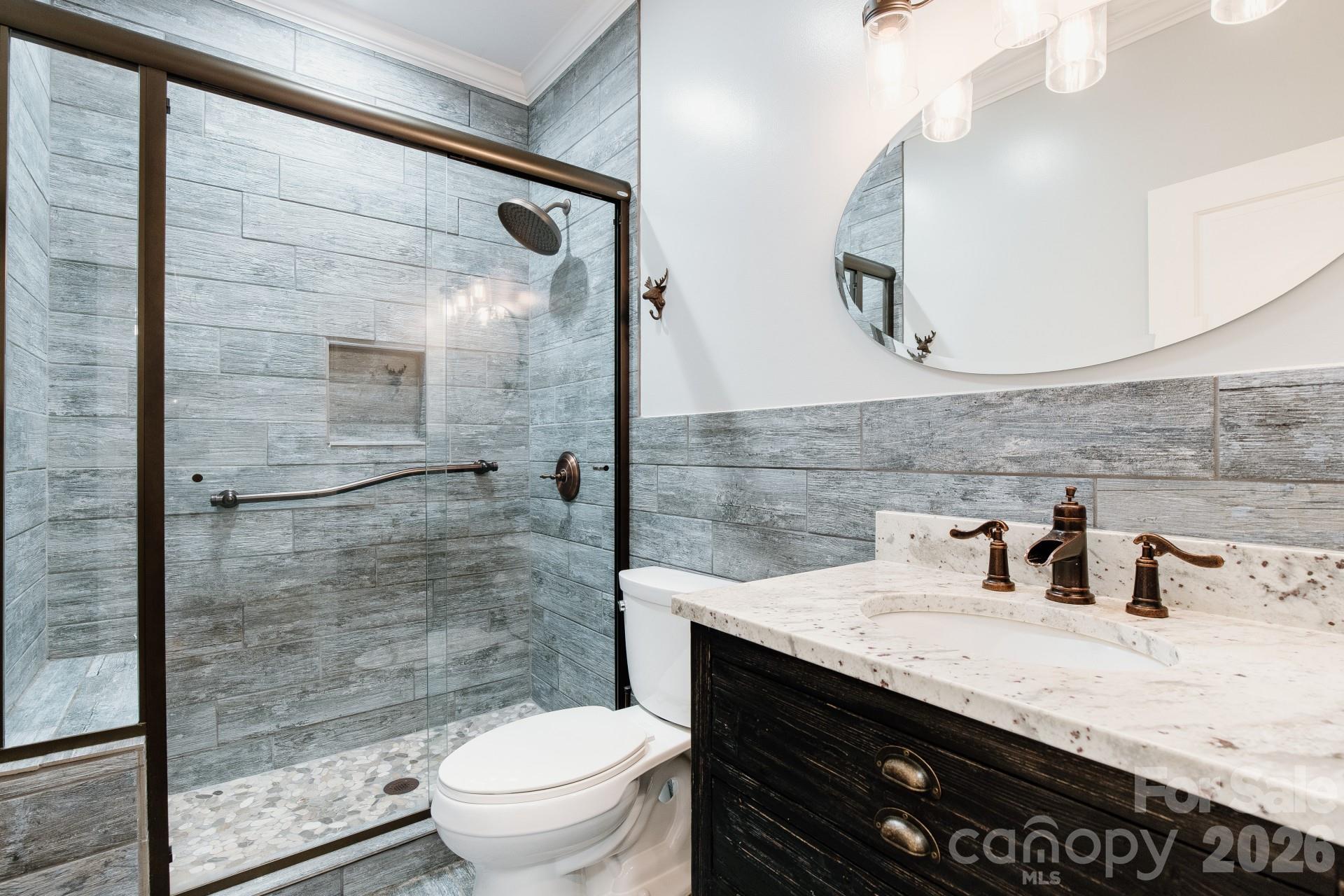 110 Mandy Lane Tryon, NC 28782 - Photo 29 of 48 a bathroom with a granite countertop sink a toilet a mirror and shower