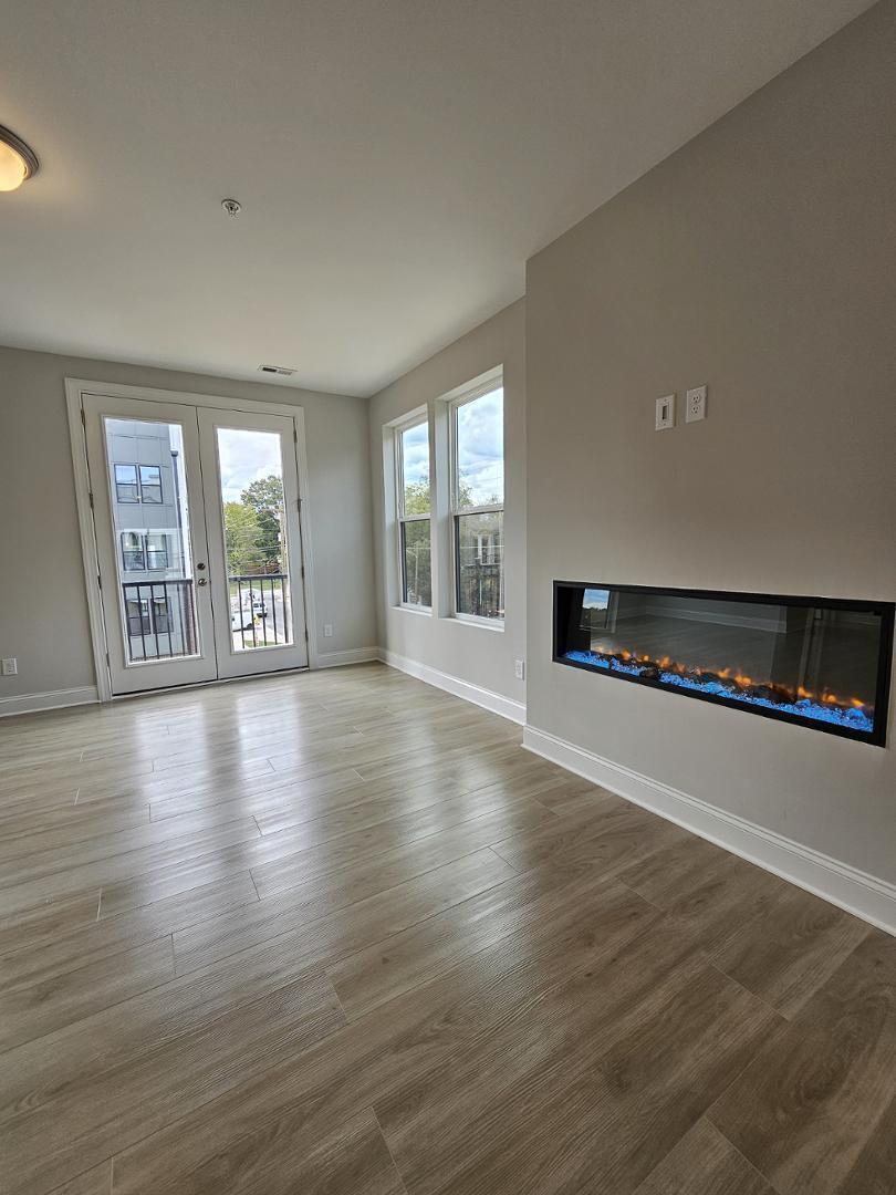 1202 Coach Station Alley, Unit 201 Raleigh, NC 27601 - Photo 2 of 16 a view of an empty room with wooden floor and a window