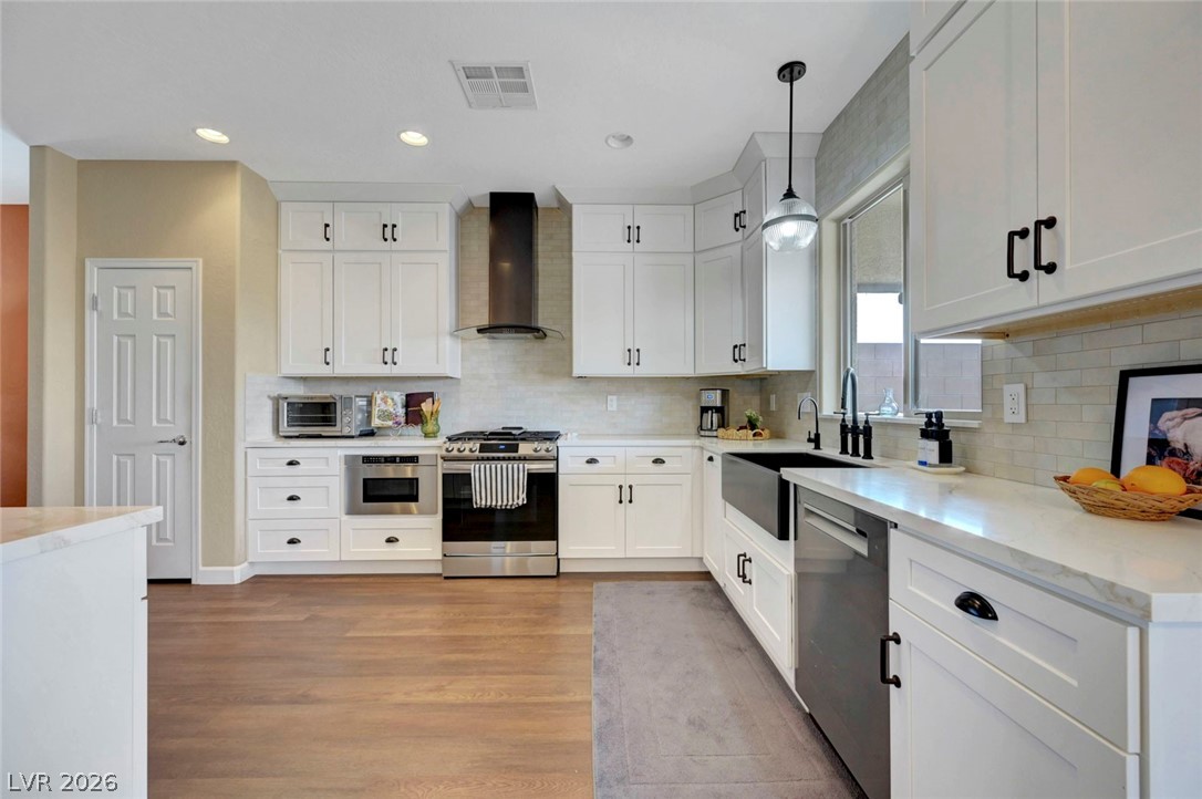 2700 Rue Montpellier Avenue Henderson, NV 89044 - Photo 14 of 39 Kitchen featuring white cabinets, stainless steel appliances, pendant lighting, and light stone countertops