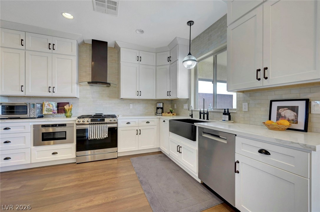2700 Rue Montpellier Avenue Henderson, NV 89044 - Photo 15 of 39 Kitchen featuring stainless steel appliances, white cabinetry, pendant lighting, light wood finished floors, and light stone countertops