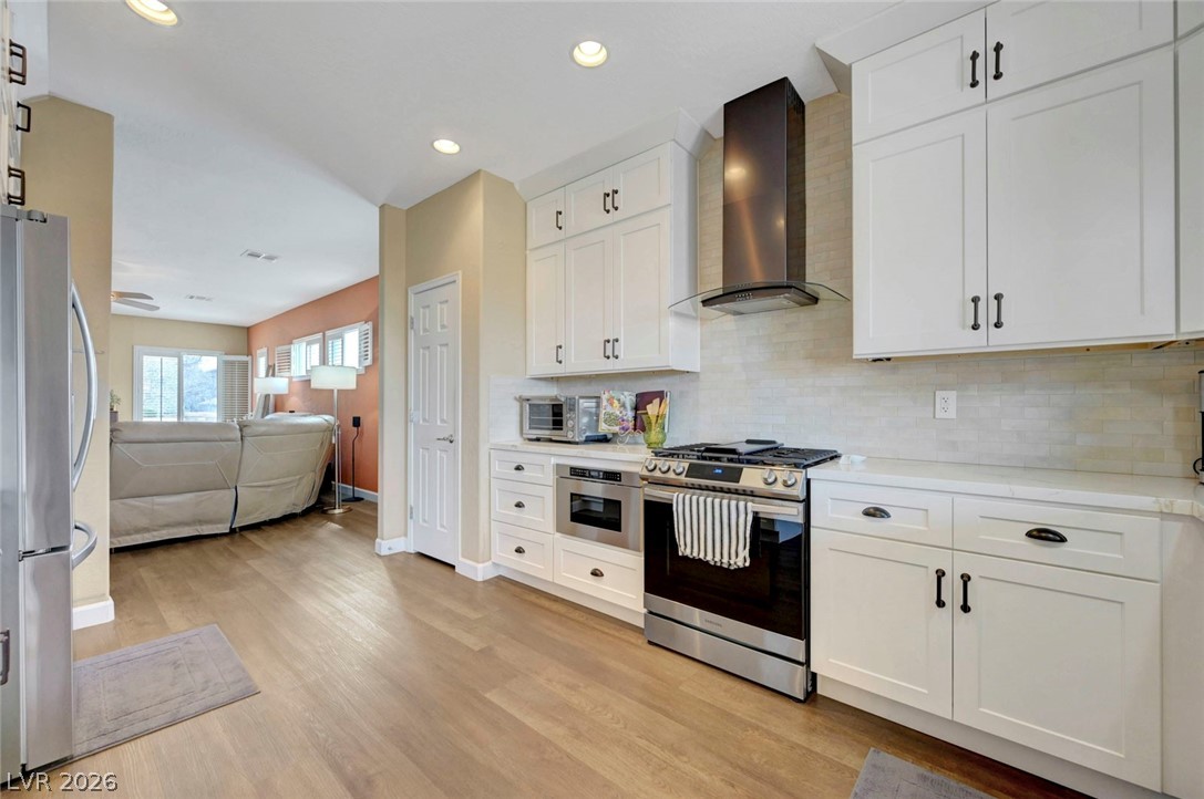 2700 Rue Montpellier Avenue Henderson, NV 89044 - Photo 38 of 39 Kitchen featuring white cabinets, stainless steel appliances, open floor plan, light wood-style flooring, and recessed lighting