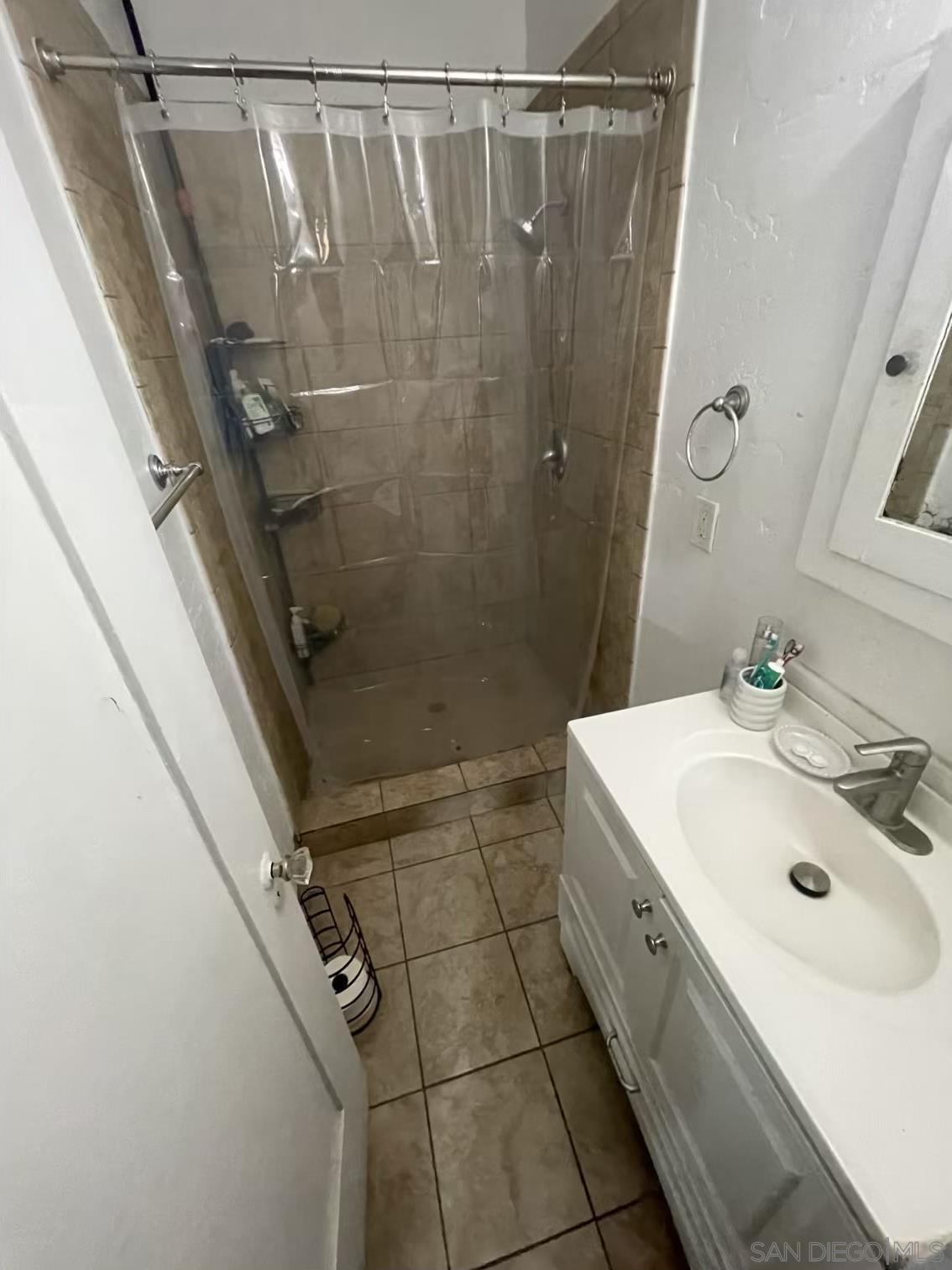4667 35th Street San Diego, CA 92116 - Photo 14 of 29 a bathroom with a sink a mirror and shower