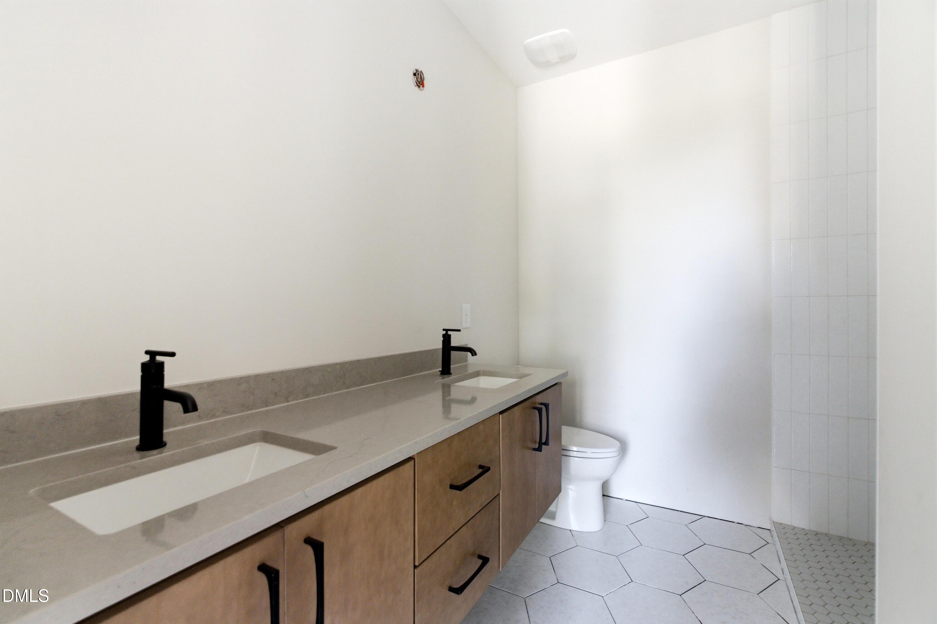720 Noble Town Way, Unit 105 Raleigh, NC 27603 - Photo 11 of 23 This primary bathroom suite features dual vanity sinks, upgraded lighting fixtures, and an oversized walk-in tile shower
