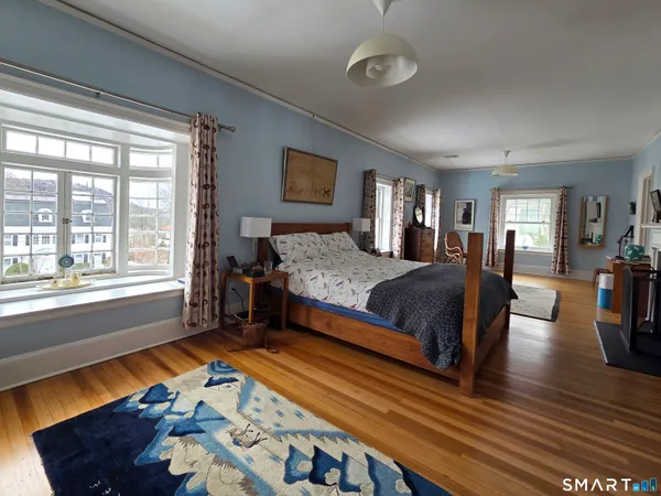 a spacious bedroom with a bed a dresser and wooden floor