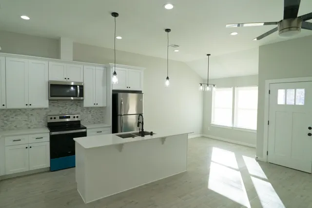 a kitchen with stainless steel appliances granite countertop a sink a stove a refrigerator and a window