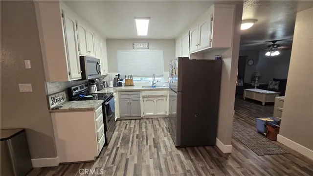 a kitchen with a refrigerator a stove top oven and wooden floor