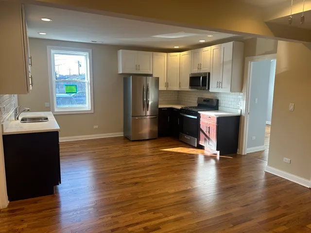 a kitchen with granite countertop wooden floors stainless steel appliances and window