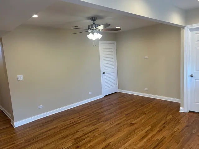 an empty room with wooden floor cabinet and windows