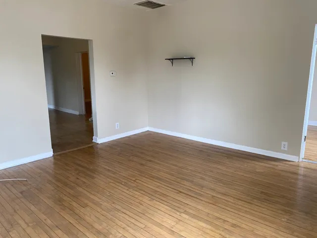 a view of an empty room with wooden floor