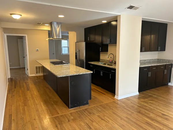 a kitchen with stainless steel appliances kitchen island granite countertop a refrigerator and a sink