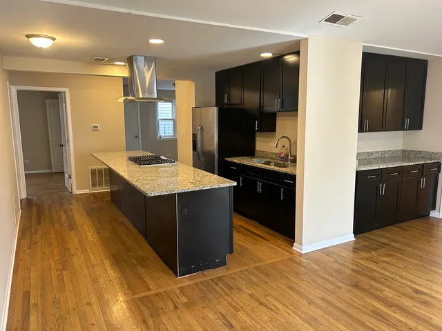 a kitchen with stainless steel appliances kitchen island granite countertop a refrigerator and a sink