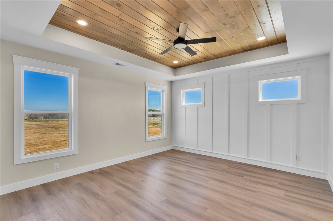 4546 Flat Rock Road Iva, SC 29655 - Photo 22 of 28 This spacious bedroom features a beautiful wood-paneled tray ceiling and durable hardwood flooring.
