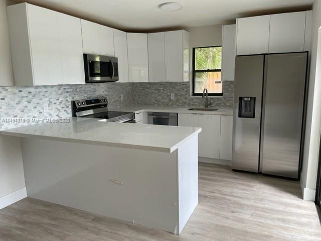 7753 Courtyard Run West, Unit 7753 Boca Raton, FL 33433 - Photo 4 of 15 a kitchen with a refrigerator a microwave a sink and cabinets