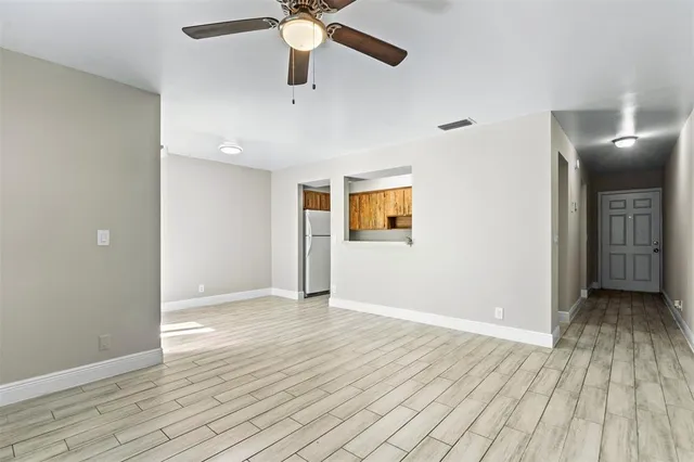 an empty room with wooden floor fan and windows