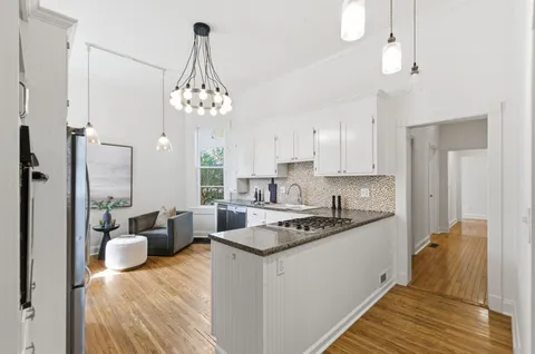 a kitchen with a refrigerator a stove a sink dishwasher and white cabinets with wooden floor