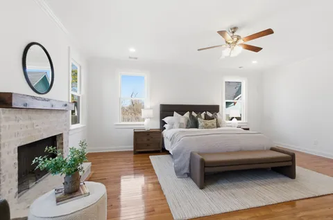 a spacious bedroom with a bed a fireplace and a potted plant