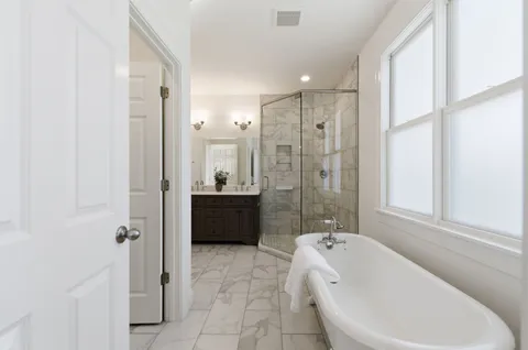 a bathroom with a tub shower sink and mirror