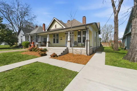 a front view of a house with a garden and trees