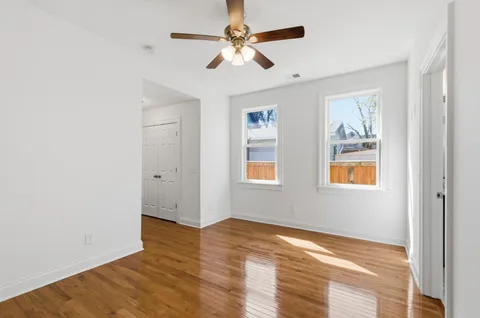 a view of an empty room with window and wooden floor