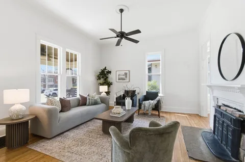 a living room with couches a fireplace and a dining table with wooden floor