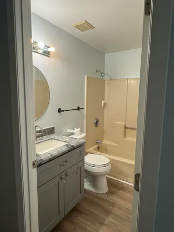 a bathroom with a granite countertop sink toilet a mirror a vanity and shower